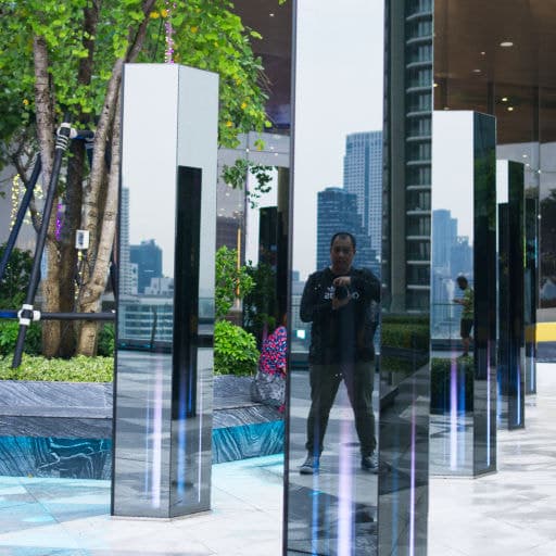 The reflection captures a man taking a photo of himself in IconSiam's park.